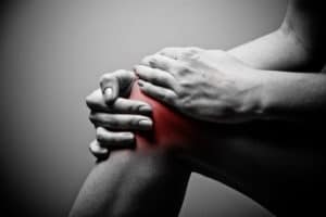 man grasping painful knee