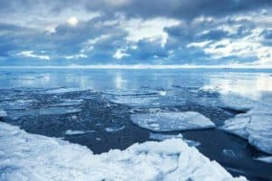 Winter coastal landscape with floating ice fragments on still cold blue water. Gulf of Finland, Russia