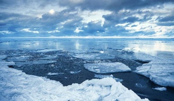 Winter coastal landscape with floating ice fragments on still cold blue water. Gulf of Finland, Russia