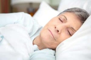 Senior woman sleeping in white bed