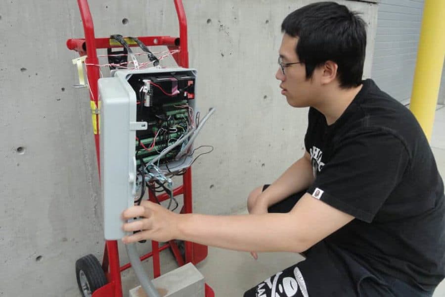 Chemical engineering student Ka Fung Wong inspects sensors that are buried under the concrete test plot.