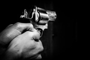 Man's hands point a revolver