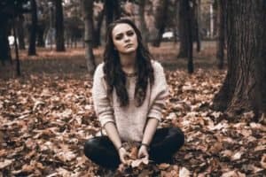 Sad woman sitting in leaves