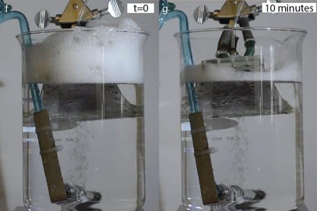 In a beaker with a constant stream of bubbles, inserting a piece of the new textured material developed by the MIT team (gray object extending into the surface at top) causes the foam buildup at the top of the beaker to dissipate almost completely within ten minutes. Courtesy of the Varanasi Lab