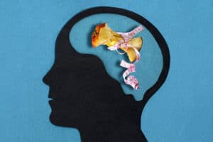 Stylized head silhouette. Brain with apple stub in measuring tape. Pathological food restriction. Anorexia nervosa. Concept of mental health and disease