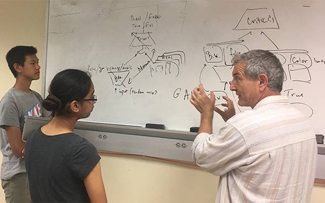During COSMOS 2019 at UC San Diego, Music prof. Shlomo Dubnov (right) discusses machine learning architecture for tool to convert musical notation between musical styles with COSMOS students, including co-author Conan Lu, a high school senior (far left).