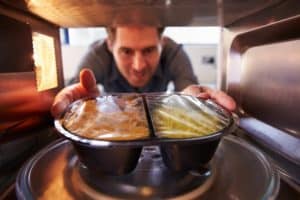 Man taking food out of microwave oven