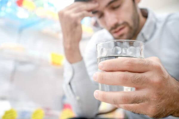 Man with drink in hand looking stressed out