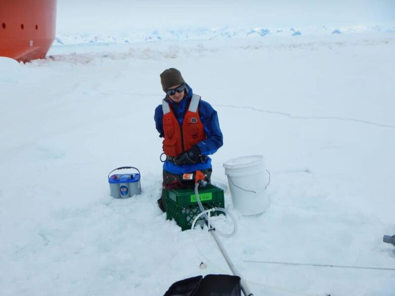 MIT-WHOI Joint Program student Henry Holm pumping seawater for lipid samples from beneath sea ice on the Western Antarctic Peninsula, 2018. This is for a WHOI-led study that conducted a global survey of lipids in the ocean in order to analyze omega-3 fatty acids. Image credit: Benjamin Van Mooy / © Woods Hole Oceanographic Institution