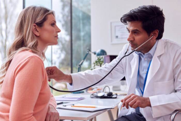 Doctor listening with stethoscope to woman's lungs