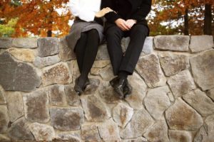 Couple sitting on a stone wall in church clothing