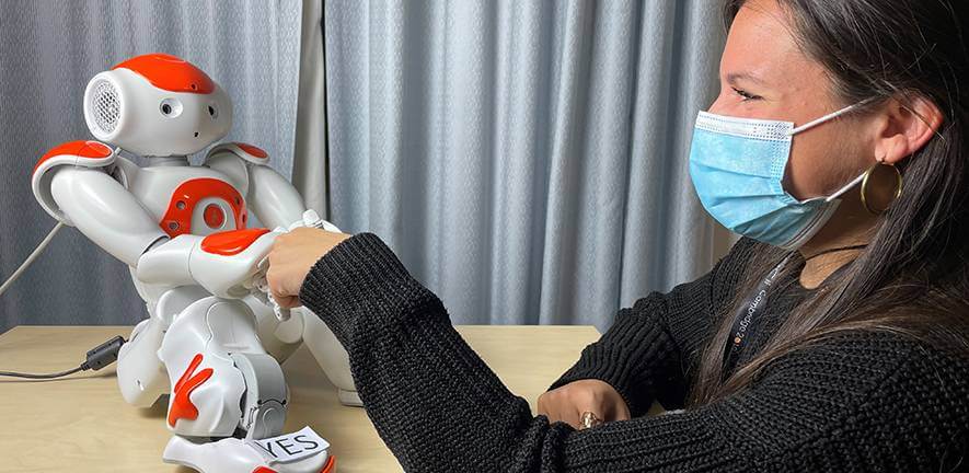 Nao robot shaking hands with study co-author Dr Micol Spitale Credit: Rachel Gardner