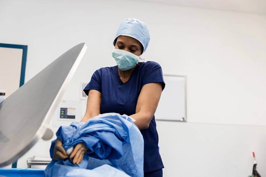 A surgeon puts a surgical gown into a waste bin. (Image credit: Getty Images)