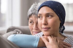 An Asian woman in her 60s embraces her mid-30s daughter who is battling cancer - stock photo