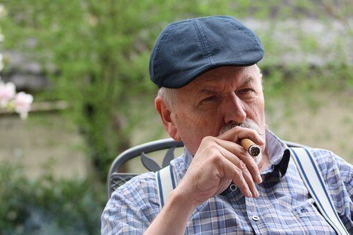 Man in hat smokes a cigar