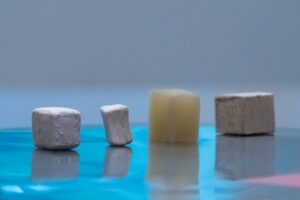 Wood pieces at different stages of modification, from natural (far right) to delignified (second from right) to dried, bleached and delignified (second from left) and MOF-infused functional wood (first on the left).