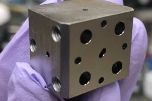 A niobium superconducting cavity. The holes lead to tunnels which intersect to trap light and atoms.