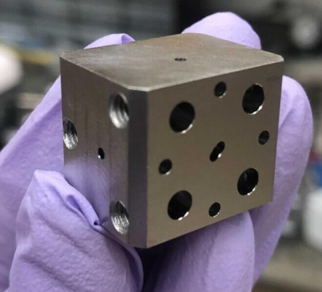 A niobium superconducting cavity. The holes lead to tunnels which intersect to trap light and atoms.