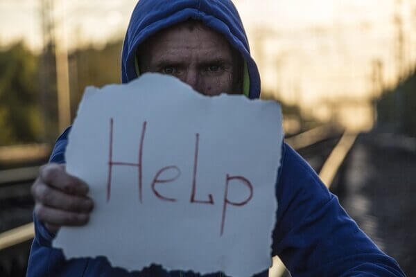 Man with handwritten sign reading "Help"
