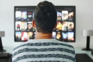 Man seen from behind watching television