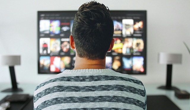 Man seen from behind watching television