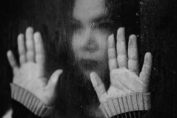 Lonely looking woman staring out of rain covered window