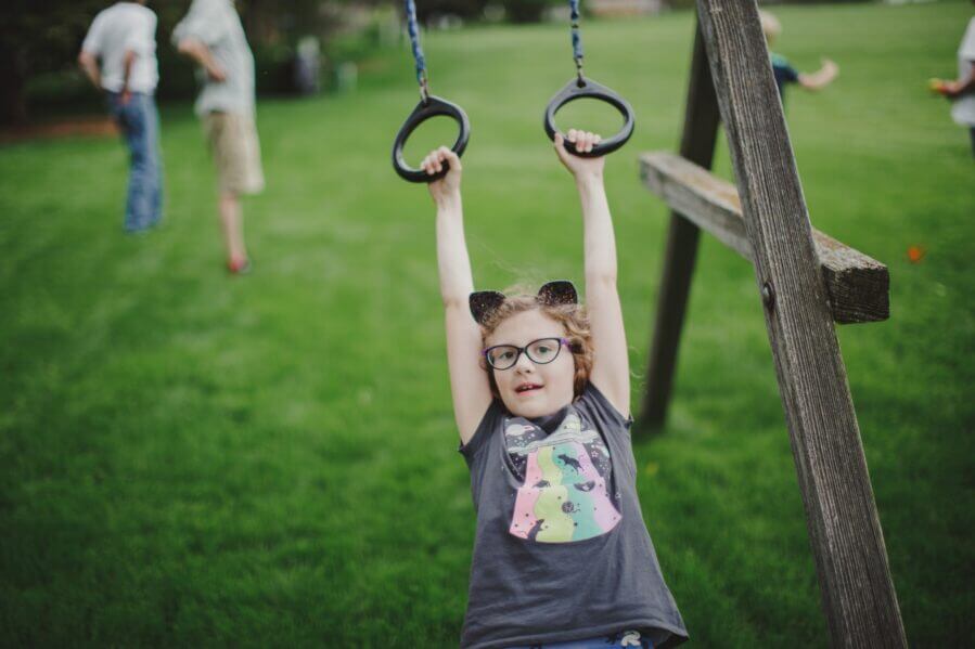 Child playing on rings at a jungle gym, wearing glasses