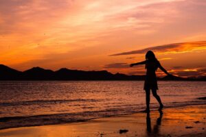 Woman dancing at sundown on the beach. Pixabay