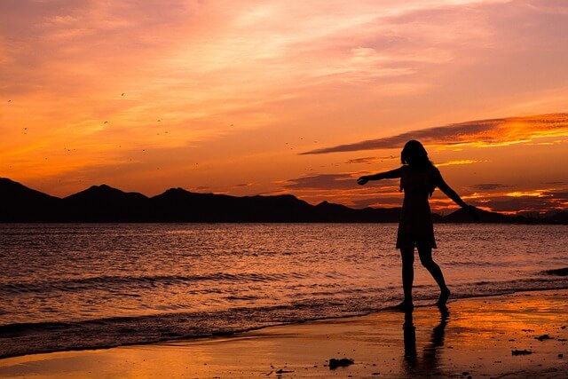 Woman dancing at sundown on the beach. Pixabay