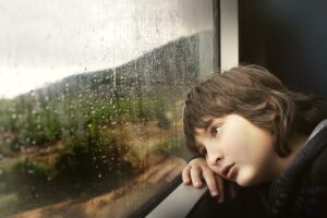 Sad boy looking out a train window. credit pixabay