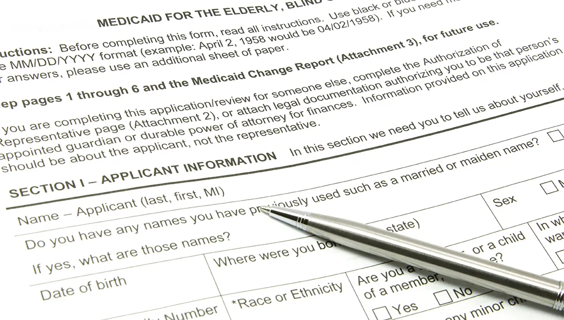 A Medicaid application ready to be filled out with a silver pen.