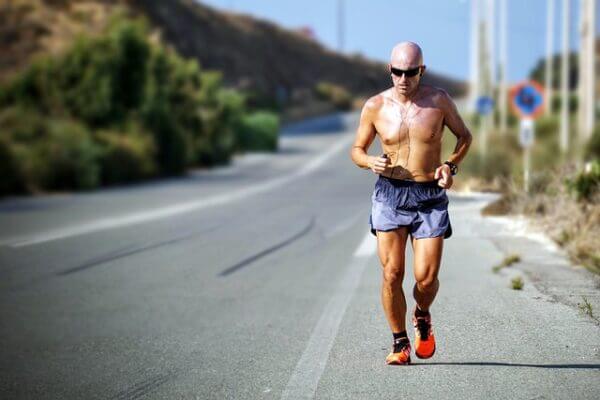 Man running shirtless on desolate road.