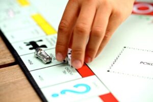 Child's hand moving a piece on the board of Monopoly. Credit Pixabay