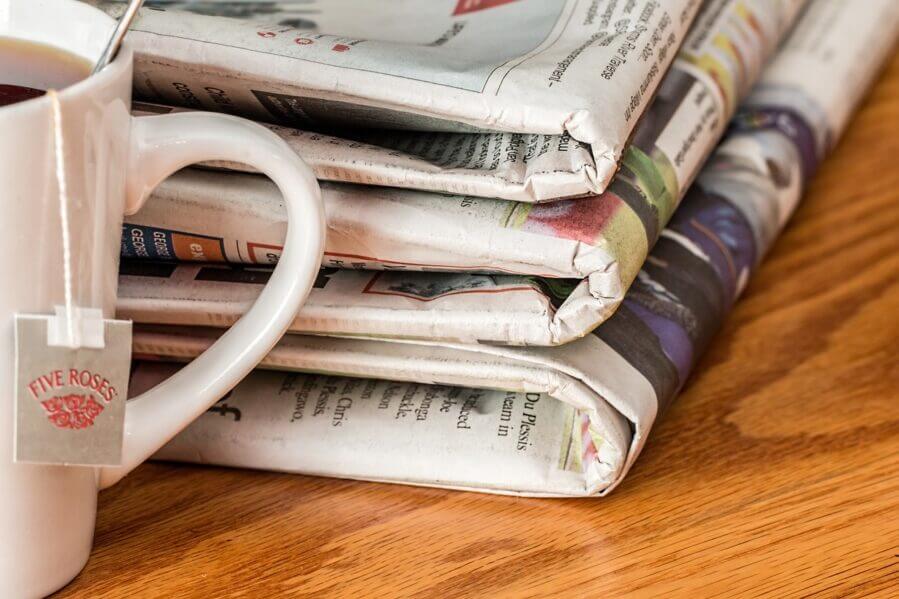 Folded newspaper next to a cup of tea. Pixabay