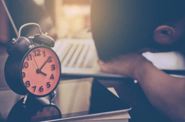 Close up of a man resting head on his desk with an alarm clock in the foregro...                    </div>

                    <div class=