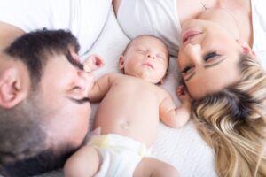Cute mother, father and baby portrait, all lying on a bed. Pixabay