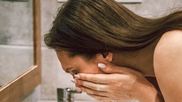 Woman rinsing her face in a bathroom sink. Pixabay