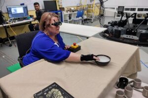 A research team member who is blind uses acoustic touch to locate and reach for an item on the table. Photo: Lil Deverell CC-BY 4.0