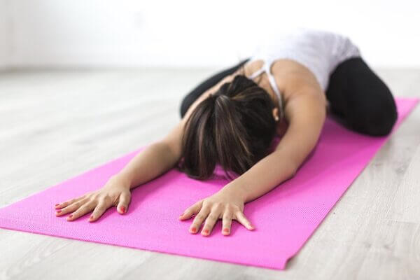Woman stretching on a pink yoga mat. Pixabay