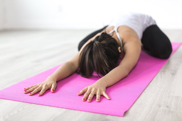 Woman stretching on a pink yoga mat. Pixabay