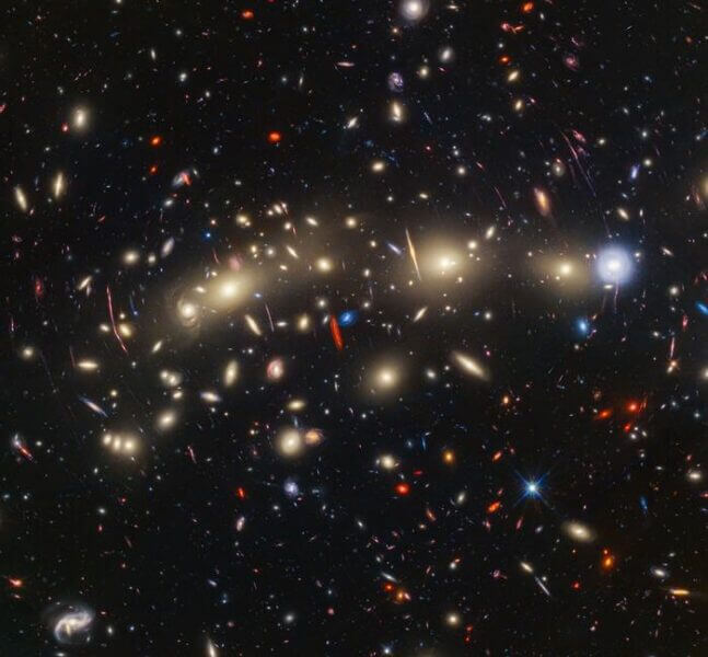 Panchromatic view of MACS0416, a galaxy cluster about 4.3 billion light-years from Earth. The image was created by combining infrared observations from NASA’s James Webb Space Telescope with visible-light data from NASA’s Hubble Space Telescope. The resulting prismatic panorama of blues and reds give clues to the distances of the galaxies.