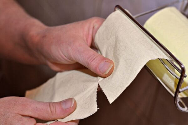 Hand tearing off some toilet paper