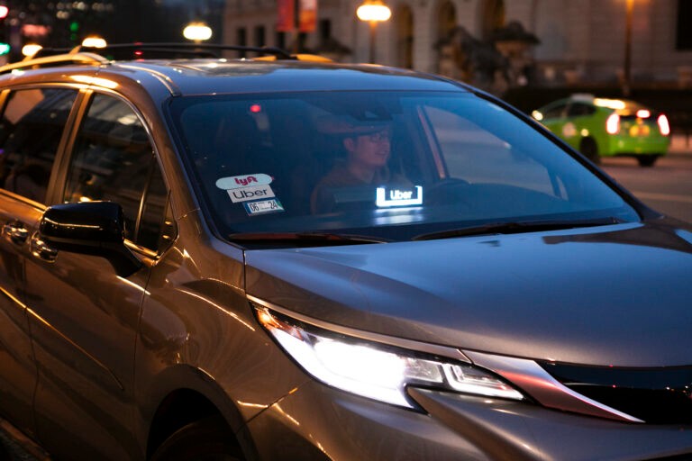 A driver with Lyft and Uber stickers on windshield