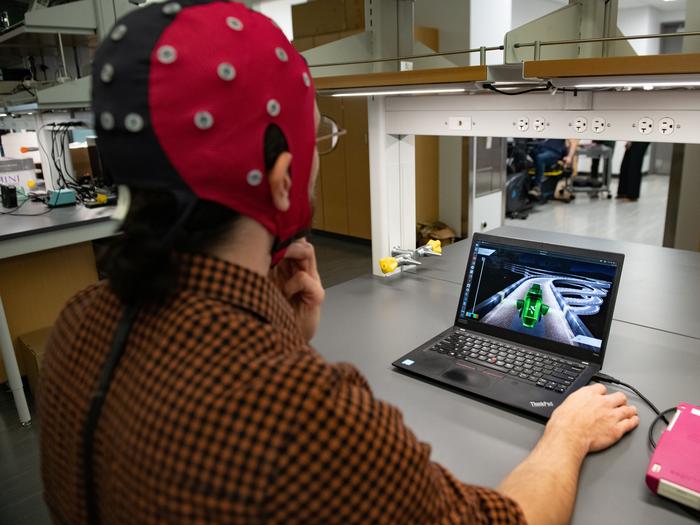 Hussein Alawieh, a graduate student in José del R. Millán's lab, wears a cap packed with electrodes that is hooked up to a computer. The electrodes gather data by measuring electrical signals from the brain, and the decoder interprets that information and translates it into game action.