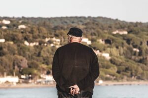 Elderly man looking at the water, seen from behind