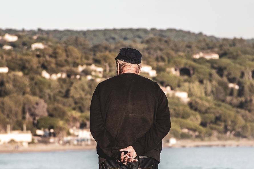 Elderly man looking at the water, seen from behind