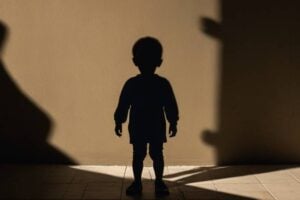 a child standing alone, with a shadow of an adult figure behind them fading away, symbolizing the loss of a parent to drug overdose.