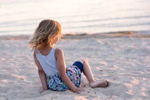 Girl sitting on the sand at beach. Pixabay