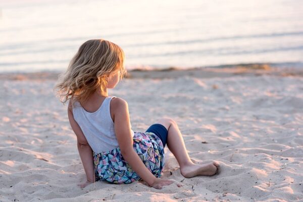 Girl sitting on the sand at beach. Pixabay