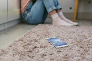 Female sittingon floor afraid of her phone which is on the carpet near her